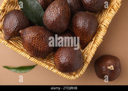 Délicieux fruits de salak dans le panier sur fond brun pâle, vue de dessus Banque D'Images