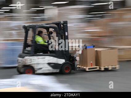 PRODUCTION - 07 décembre 2023, Hesse, Francfort-sur-le-main : un employé conduit un chariot élévateur dans le hall de fret aérien DB Schenker à Cargo City South à l'aéroport de Francfort (tourné avec une vitesse d'obturation plus lente). Le fret aérien permet de transporter une grande variété d’objets sur les continents. À l'approche de Noël, les choses doivent bouger particulièrement vite. (À dpa « quand chaque centimètre compte - poussée de fin d'année dans le hall de fret aérien ») photo : Arne Dedert/dpa Banque D'Images