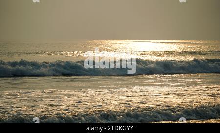 Close up vague douce a rodé la plage de sable, fond d'été. Belles vagues de mer avec mousse de couleur dorée isolée. Banque D'Images