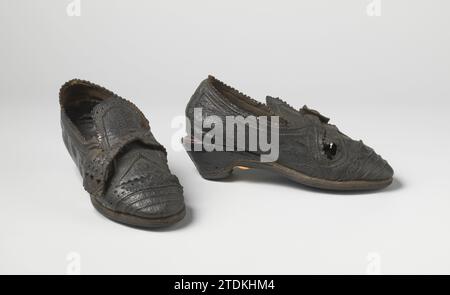 Chaussure pour femmes en cuir de boeuf avec languette droite, décorée de perforations et de cartels, avec talon bas, anonyme, c. 1600 - c. 1650 Chaussure en cuir noir. Gauche-droite symétrique. Le couvercle est dans une valve, sur laquelle une courroie est fermée. Le talon bloc est partiellement lâche, où une garniture de cuir rouge est appliquée. Décoration de deux rampes, perforations et conférences. (Lié à BK-NM-8430). Nord des pays-Bas entier : cuir. Chaussure perforante en cuir noir. Gauche-droite symétrique. Le couvercle est dans une valve, sur laquelle une courroie est fermée. Le talon bloc est partiellement lâche, où une garniture de cuir rouge est appliquée. Banque D'Images