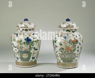 Pot couvert de balustre avec paniers de fleurs, sprays de fleurs et insectes, anonyme, c. 1700 - c. 1724 pot de couvercle en porcelaine en forme de balus, peint sur la glaçure en bleu, rouge, vert, jaune, aubergine, noir et or. Sur le ventre quatre fois un panier de fleurs avec aster, pivoine, prunus, pluie bleue, lotus, chrysanthème et iris. Un panier avec des motifs Shishi et Ruyi et un panier avec des Feng Huangs et des caractères chinois. Entre les paniers, les branches de fleurs lâches et les insectes. Au-dessus du pied une bande avec des motifs de feuilles stylisés. Sur l'épaulement un lien avec le travail de l'arbre. Le cou avec des branches de fleurs et des papillons Banque D'Images