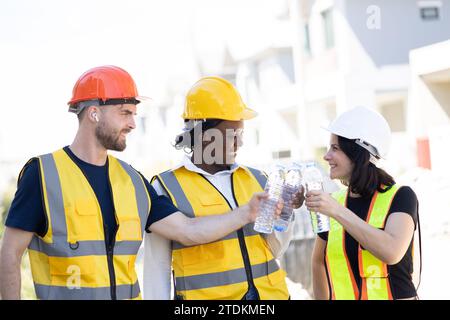 Équipe d'ingénieurs de travailleurs en bonne santé assoiffée buvant de l'eau propre dans la température chaude saison d'été pour se détendre frais sur le lieu de travail du chantier de construction. Banque D'Images