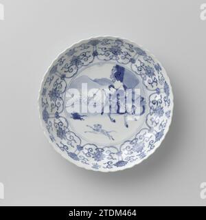 Soucoupe-plat avec scène de chasse, rouleaux de lotus et symboles auspicieux, anonyme, c. 1700 - c. 1724 bol en porcelaine avec mur rond, nervuré et bord festonné, peint en bleu sous-laque. Sur le plat une scène de chasse avec deux cavaliers armés avec un chien dans un paysage, la chasse d'un animal ; le bord avec une bande connectée de Lotusranken avec motif Ruyi, entre lesquels les huit symboles chanceux (chakra, coquille, parasol, canopée, lotus, vase, pêche, noeud infini) ; le dos avec seize branches de fleurs lâches. Marqué sur le dessous avec la marque à six caractères de Keizer Chenghua dans un double cercle. Bleu blanc Banque D'Images