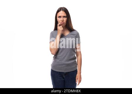 jeune surprise bouleversée femme brune européenne vêtue d'un t-shirt de base gris avec maquette de marque Banque D'Images
