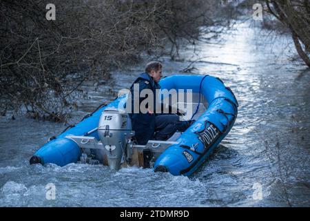 Bingen Hitzkofen, Allemagne. 19 décembre 2023. Un policier traverse les eaux du Lauchert en bateau. Un enfant de deux ans est porté disparu dans la municipalité depuis avant-hier. La fillette de deux ans avait probablement quitté la maison de ses parents en pyjama dans un moment inaperçu dimanche après-midi. Jusqu'à présent, les fonctionnaires supposent que c'était un accident. Crédit : Christoph Schmidt/dpa/Alamy Live News Banque D'Images