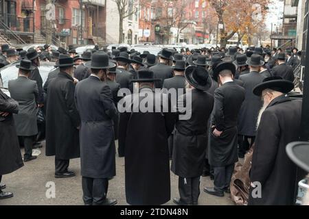 Des hommes juifs orthodoxes vêtus de noir assistent aux funérailles d'un rabbin hassidique et écoutent un éloge. À Brooklyn, New York. Banque D'Images