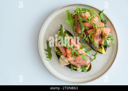 Toast de seigle avec saumon, avocat, sauce hollandaise et roquette, vue de dessus. Banque D'Images