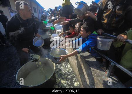 Rafah, Territoires palestiniens. 19 décembre 2023. Les Palestiniens se rassemblent avec des pots pour recevoir de la nourriture dans un point de don fourni par une organisation caritative à Rafah, dans le sud de la bande de Gaza. Crédit : Mohammed Talatene/dpa/Alamy Live News Banque D'Images