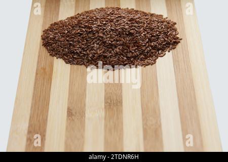De nombreuses graines brutes de lin reposent sur une planche de cuisine en bois. Ingrédient cru de boulangerie. Vue de dessus. Foyer de graines Banque D'Images