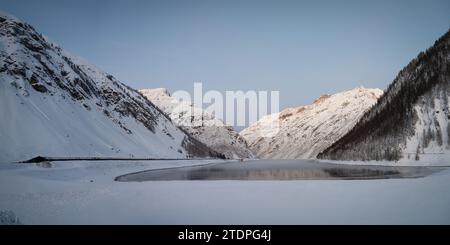 Vue panoramique hivernale du lac Lago di Livigno et galerie routière en Italie Banque D'Images
