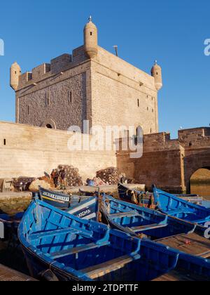 Bateaux de pêche bleus et filets de pêche près de la tour du port de pêche dans la ville d'Essaouira, Maroc. 19 décembre 2023 Banque D'Images