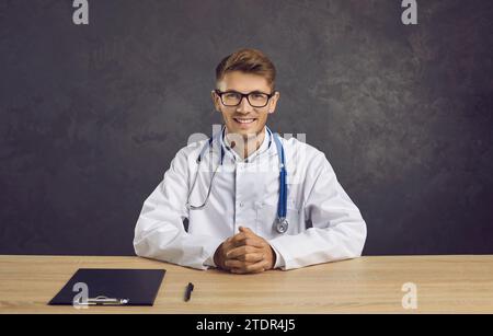 Portrait de médecin masculin souriant confiant et amical sur fond de béton gris. Banque D'Images