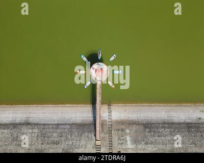 Vue aérienne d'une pluralité de planches SUP formant une fleur autour d'un objet en béton sur le lac avec deux femelles reposant au soleil. Banque D'Images