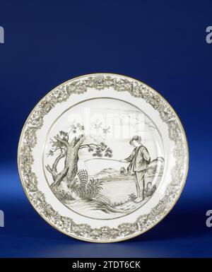 Plaque avec une image du Jeune pêcheur, anonyme, c. 1740 - c. 1760 plaque en porcelaine, peinte sur la glaçure en noir et or. Sur le plat un jeune homme avec une tige sur les rives d'une rivière, derrière lui un panier, une cruche et du poisson et un arbre mort et deux pièges pour lui, un village avec des montagnes de l'autre côté de la rivière ; le bord avec un motif décoratif européen. Au bas, deux vieilles étiquettes portent l'inscription 'F. Bodenham/ Elmhurst, Hereford/ 52' et '16/ The Fisherman/ [...]'. Présentation basée sur l'estampe le jeune pêcheur d'Abraham Bloemaert (1564-1651). Performance européenne à encre de Chine. Chine Banque D'Images