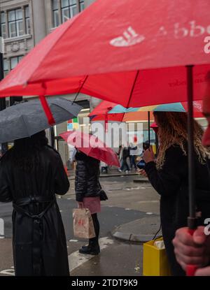 Les acheteurs de Noël profitent des soldes des fêtes de fin d'année sur Oxford Circus, dans le West End de Londres, par une journée hivernale humide, en Angleterre, au Royaume-Uni Banque D'Images