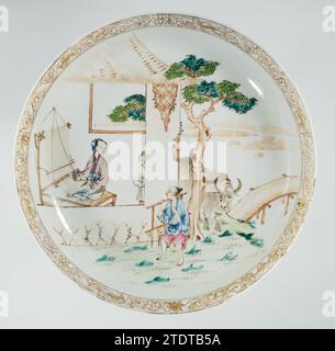 Soucoupe-plat avec le troupeau et la tisserand girl, c. 1730 - c. 1745 bol en porcelaine avec mur rond, peint sur la glaçure en bleu, rouge, rose, vert, jaune, marron, noir et or. Sur le devant d'un pavillon près d'une rivière avec un berger, des bœufs sont attachés à un arbre, et un tisserand dans le pavillon, une deuxième femme regarde autour du coin du cadre ; le bord intérieur avec des boissons de lotus. Famle Rose. Porcelaine de Chine. glaçage. Or (métal) peinture / dorure / vitrification bol en porcelaine avec paroi ronde, peint sur la glaçure en bleu, rouge, rose, vert, jaune, marron, noir et or. Sur le devant un pavillon près d'un ri Banque D'Images