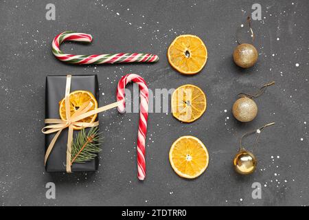 Boîte cadeau avec tranches d'orange séchées, boules de Noël et cannes de bonbons sur fond noir Banque D'Images