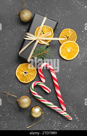 Boîte cadeau avec tranches d'orange séchées, boules de Noël et cannes de bonbons sur fond noir Banque D'Images