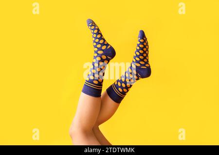 Jambes de jeune femme en chaussettes pointillées violettes sur fond jaune Banque D'Images