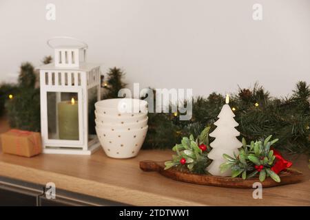 Bougies avec bols, GUI et branches d'arbre de Noël sur la table dans la cuisine Banque D'Images