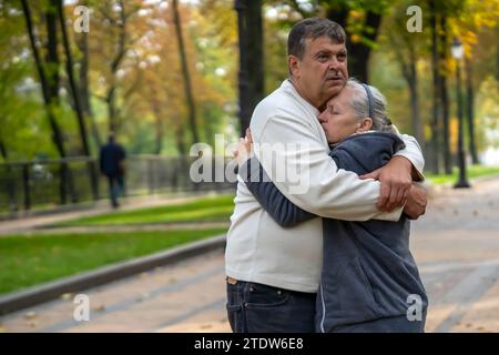 Un couple de personnes âgées s'étreint dans le parc pendant la promenade. Banque D'Images