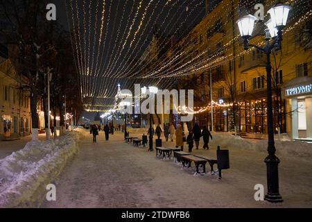 Ryazan, Russie - 16 décembre 2023 : rue de la ville en soirée d'hiver avec guirlandes festives et gens qui marchent Banque D'Images