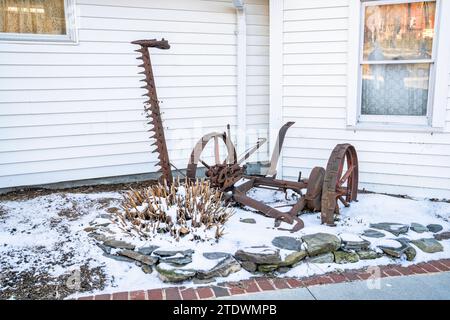 Une pièce d'équipement agricole antique se trouve dans la neige devant le Daniel Boone Inn à Boone, en Caroline du Nord. Banque D'Images