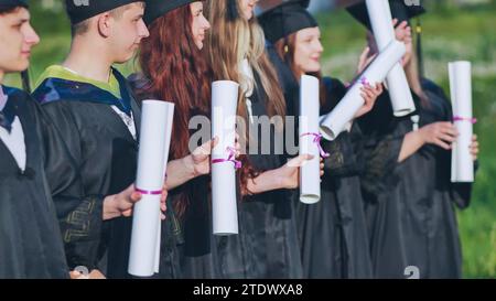 Rouleaux de diplômes entre les mains d'un groupe de diplômés. Banque D'Images