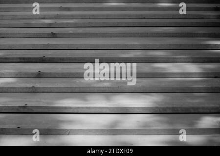 Symphonie abstraite de planches de bois, gracieusement arrangées en harmonie décalée, peinte par les douces ombres projetées par le feuillage aérien - une poésie visuelle. Banque D'Images