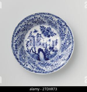 Soucoupe avec panneaux torsadés et sprays de fleurs, anonyme, c. 1680 - c. 1720 soucoupe en porcelaine avec mur rond modelé en dix cours torsadés, peinte en bleu sous-couche. Sur le plat un rocher avec une branche de fleur, des plantes et deux papillons ; Une branche de fleur sur le mur dans chaque boîte ; le bord avec une boisson de fleur ; sur le dos aussi une branche de fleur dans chaque boîte. Marqué sur la face inférieure du caractère chinois « Fú » dans un double cercle. Une puce dans le bord. Bleu blanc. Porcelaine de Chine. glaçage. Cobalt (minéral) peinture / vitrification soucoupe en porcelaine avec paroi ronde modelée en dix parcours torsadés, peinte Banque D'Images