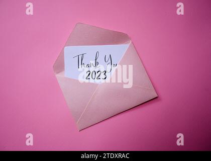 Carte de remerciement 2023 dans une enveloppe blanche avec fond de couleur. bye-bye 2023, et bienvenue 2024. Banque D'Images