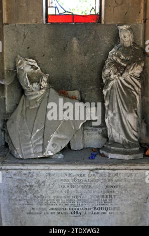 Un buste recouvert de poussière et brisé et une sculpture se trouvent à l'intérieur d'un mausolée dans le cimetière historique du Père Lachaise à Paris. Banque D'Images