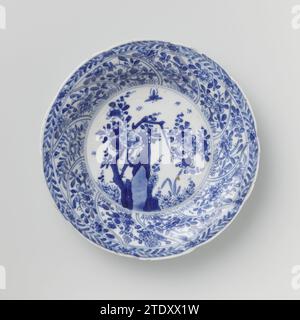 Soucoupe avec panneaux torsadés et sprays de fleurs, anonyme, c. 1680 - c. 1720 soucoupe en porcelaine avec mur rond modelé en dix cours torsadés, peinte en bleu sous-couche. Sur le plat un rocher avec une branche de fleur, des plantes et un papillon ; Une branche de fleur sur le mur dans chaque boîte ; le bord avec une boisson de fleur ; sur le dos aussi une branche de fleur dans chaque boîte. Marqué sur la face inférieure du caractère chinois « Fú » dans un double cercle. Quelques copeaux dans le bord. Bleu blanc. Porcelaine de Chine. glaçage. Cobalt (minéral) peinture / vitrification soucoupe en porcelaine avec mur rond modelé en dix cours torsadés, peint en Banque D'Images