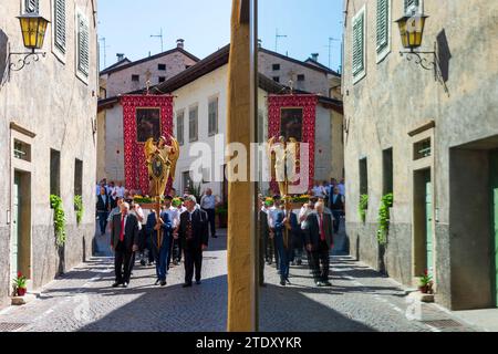 Tramin an der Weinstraße (Termeno sulla Strada del Vino) : procession du corpus Christi, personnages en vêtements traditionnels, drapeaux d'église, reflet dans la fenêtre Banque D'Images