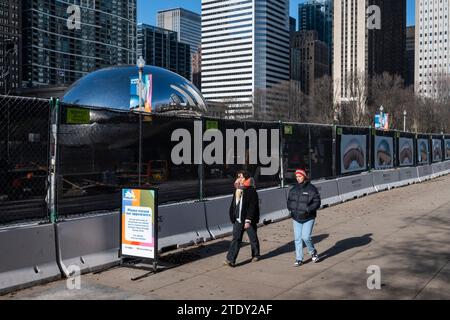 Chicago, États-Unis. 19 décembre 2023. Les touristes passent une clôture entourant la zone autour de l'installation artistique appelée Cloud Gate dans Millennium Park par l'artiste britannique Anish Kapoor. Populairement connue sous son surnom The Bean, l’installation artistique est l’une des principales attractions touristiques de Chicago. Les travaux de réparation se poursuivront jusqu'au printemps 2024 avec des améliorations au pavage et d'autres réparations. Crédit : Stephen Chung / Alamy Live News Banque D'Images