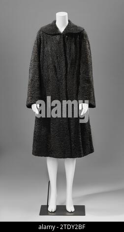 Manteau de fourrure longueur mollet, Splitter Frères, 1950 - 1960 Manteau en fourrure d'astrakan noir avec col plat rond. Le modèle large, cadencant, demi-longueur se ferme au milieu des crochets et des yeux. Les manches sont larges vers le haut. La veste est doublée de satin noir. Sur le devant droit, le monogramme 'GB' (Germaine Brusse) est incorporé dans le satin en relief. Une étiquette est cousue dans le col de la veste avec : soie 'splitter/ Frères/ The Hague-Amsterdam' Amsterdam. Manteau en fourrure d'astrakan noir avec col plat rond. Le modèle large, cadencant, demi-longueur se ferme au milieu des crochets et des yeux. Les manches sont larges vers le haut Banque D'Images