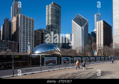 Chicago, États-Unis. 19 décembre 2023. Les touristes passent une clôture entourant la zone autour de l'installation artistique appelée Cloud Gate dans Millennium Park par l'artiste britannique Anish Kapoor. Populairement connue sous son surnom The Bean, l’installation artistique est l’une des principales attractions touristiques de Chicago. Les travaux de réparation se poursuivront jusqu'au printemps 2024 avec des améliorations au pavage et d'autres réparations. Crédit : Stephen Chung / Alamy Live News Banque D'Images