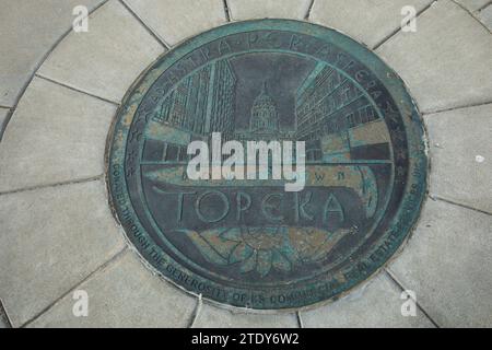 Topeka, Kansas, États-Unis - 17 juin 2023 : la lumière de l'après-midi brille sur un couvercle spécial de trou d'homme d'égout Topeka moulé. Banque D'Images