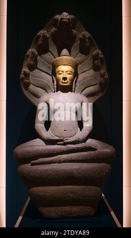 Une belle statue en pierre de Bouddah assise sculptée avec un visage en or et une tête de serpent Nagas. À l'intérieur d'une galerie au Maha Surasinghanat Building à Banque D'Images