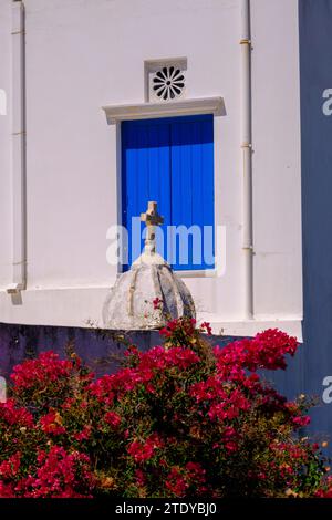 Façade d'une maison blanchie à la chaux avec des fenêtres bleues, et des fleurs de bougainvilliers Banque D'Images