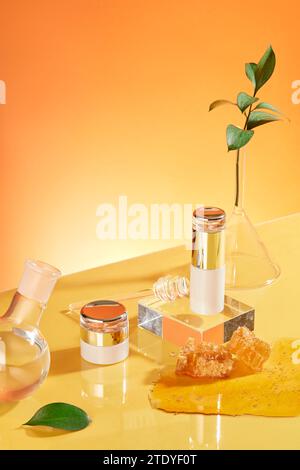 Un ensemble cosmétique au design luxueux est exposé avec de la verrerie et du miel sur un fond orange. Concept de soins de la peau avec des ingrédients naturels. Banque D'Images