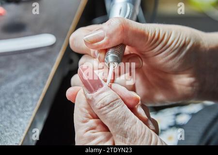 Témoin de l'expertise d'un technicien d'ongles comme ils appliquent habilement des extensions d'ongles de gel, polir les ongles savamment, et utiliser une machine de manucure à crea Banque D'Images