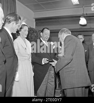 L'invité remet au directeur de l'usine Jan van Abbe (au centre avec corsage) une boîte, le co-directeur Albert van Abbe (à gauche) et une femme (probablement épouse de Jan ou Albert) regardent sur ca. 1950 Banque D'Images