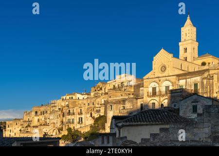 Matera, Italie - 26 novembre 2023 : vue sur la cathédrale historique de Maratea et les maisons en pierre des Sassi di Matera dans la lumière dorée chaude du soir Banque D'Images