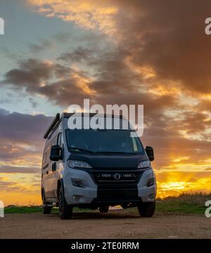 Un camping-car gris garé sur les rives du golfe de Tarente dans les Pouilles au coucher du soleil Banque D'Images