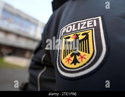 Karlsruhe, Allemagne. 20 décembre 2023. Un officier de police fédérale se tient devant la Cour constitutionnelle fédérale, son uniforme portant un blason avec un aigle fédéral et le mot "Polizei" (police). Le premier Sénat de la Cour est en train d'entendre une affaire sur la "Loi sur l'Office fédéral de police criminelle - plateformes de données". Le tribunal examine les pouvoirs des autorités de sécurité dans la lutte contre le terrorisme Credit : Uli Deck/dpa/Alamy Live News Banque D'Images