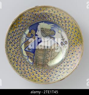 Plat avec une jeune femme, anonyme, c. 1515 - c. 1525 plat rond de majolique peinte multicolore, avec un plat approfondi. Sur l'appartement une image d'une jeune femme désirait partir. A gauche d'elle une banderolle avec l'inscription : VM Bel Moririre TVTA la Vita Onora (une mort propre honore toute la vie). Un motif écailleux sur le bord. Le plat est peint en bleu et Goudluster. Confondre la faïence. glaçure d'étain. glaçure au plomb. Glaçage brillant majolique plat rond de majolique peinte multicolore, avec un plat approfondi. Sur l'appartement une image d'une jeune femme désirait partir. Gauche d'elle une banderolle avec l'inscr Banque D'Images