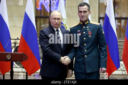 Moscou, Russie. 19 décembre 2023. Le président russe Vladimir Poutine, à gauche, serre la main du lieutenant Temirlan Abutalimov après avoir remis la médaille d’or au Centre de contrôle de la Défense nationale, le 19 décembre 2023 à Moscou, en Russie. Crédit : Mikhail Klimentyev/Kremlin Pool/Alamy Live News Banque D'Images