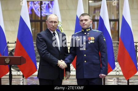 Moscou, Russie. 19 décembre 2023. Le président russe Vladimir Poutine, à gauche, serre la main du sergent junior Viatcheslav Matskevitch après avoir remis la médaille d’or au Centre de contrôle de la Défense nationale, le 19 décembre 2023 à Moscou, en Russie. Crédit : Mikhail Klimentyev/Kremlin Pool/Alamy Live News Banque D'Images