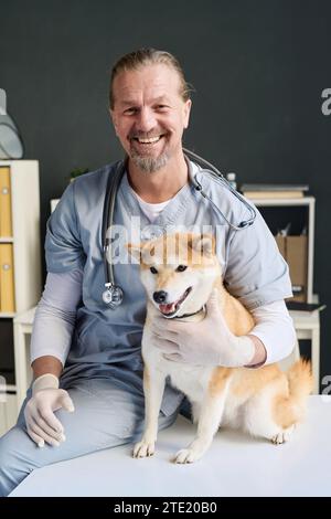 Vétérinaire joyeux posant avec son patient canin au bureau du vétérinaire pendant le rendez-vous Banque D'Images